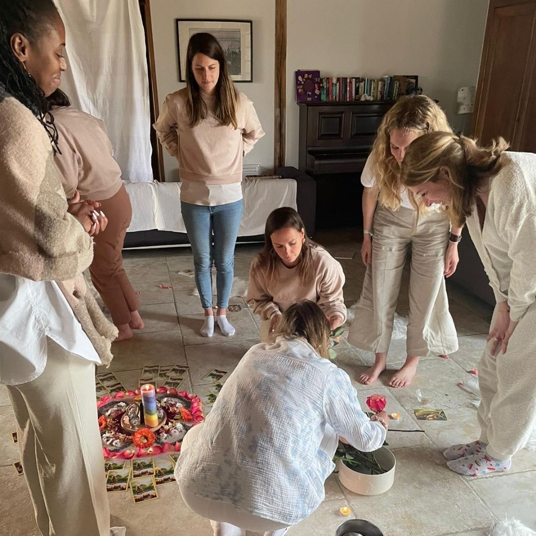 Cercle de femmes autour d’un rituel de guérison avec autel fleuri, oracle et tambours