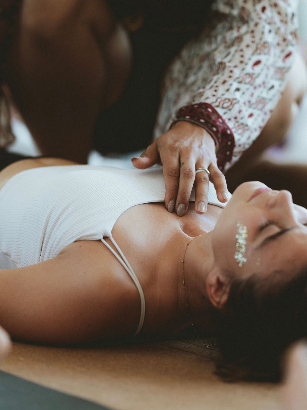 Facilitatrice posant sa main sur le cœur d’un participant pour soutenir le processus de guérison en breathwork.
