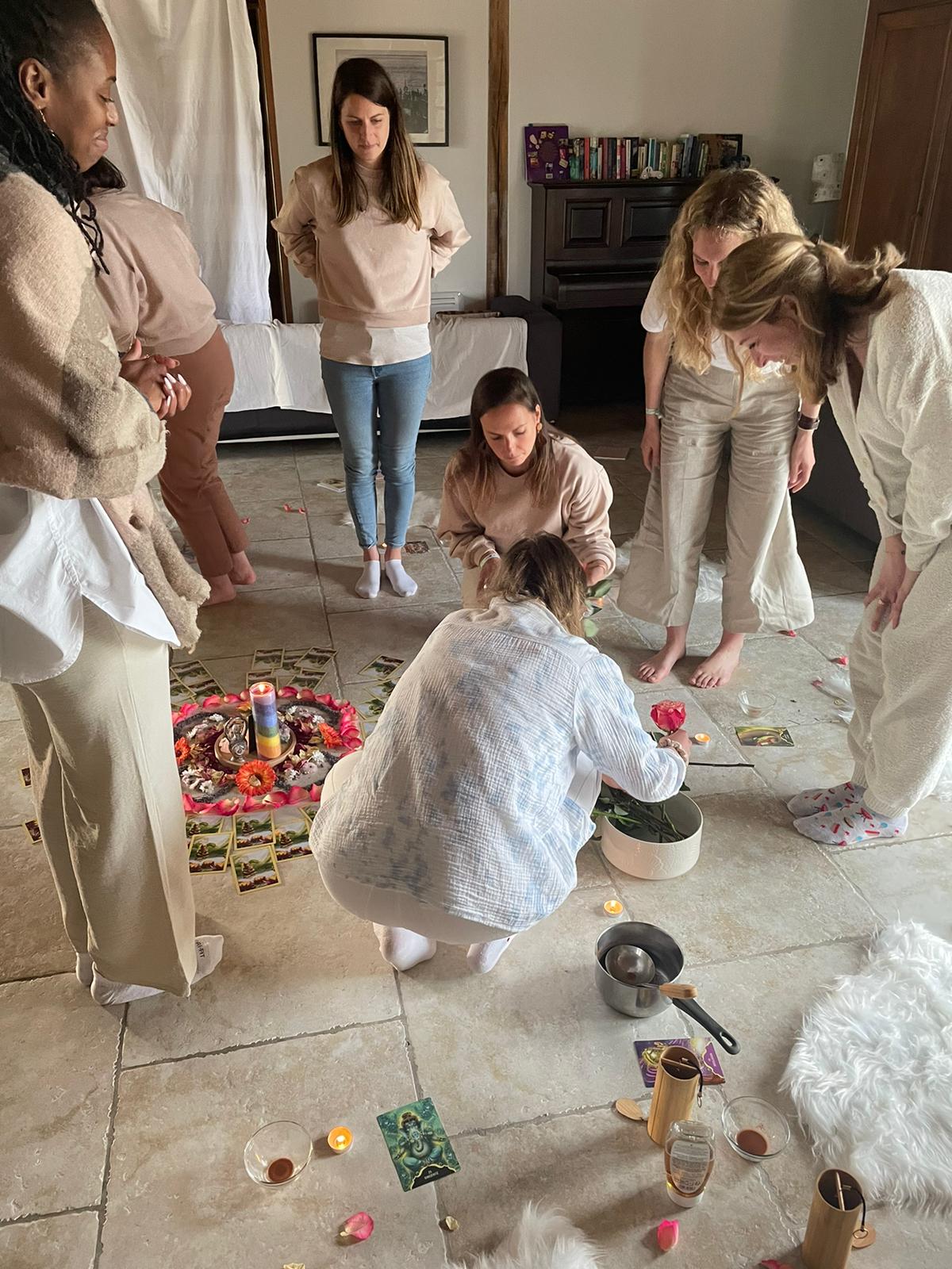 Cercle de femmes autour d’un rituel de guérison avec autel fleuri, oracle et tambours