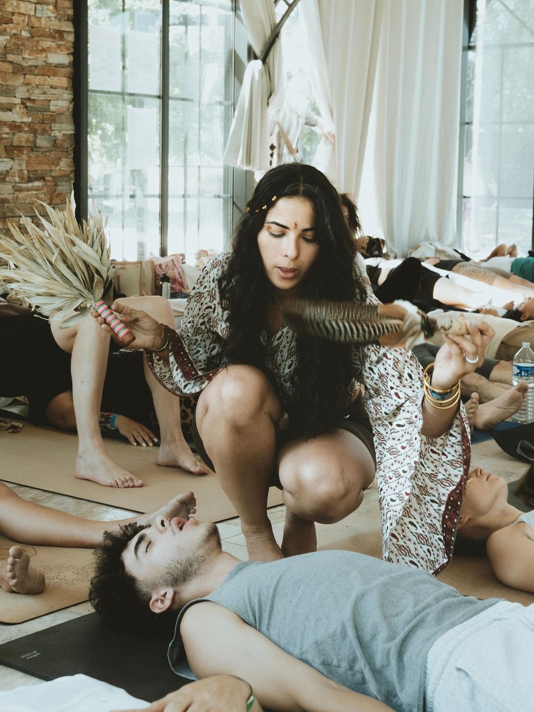 Facilitatrice guidant une séance de breathwork avec une plume rituelle, accompagnement énergétique et libération émotionnelle.