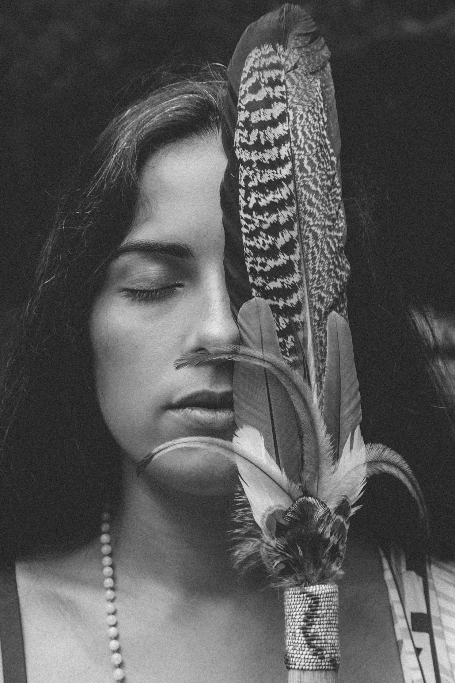 Portrait de Debby, thérapeute holistique et femme-médecine, tenant une plume comme symbole de chamanisme amazonien et de reconnexion spirituelle.