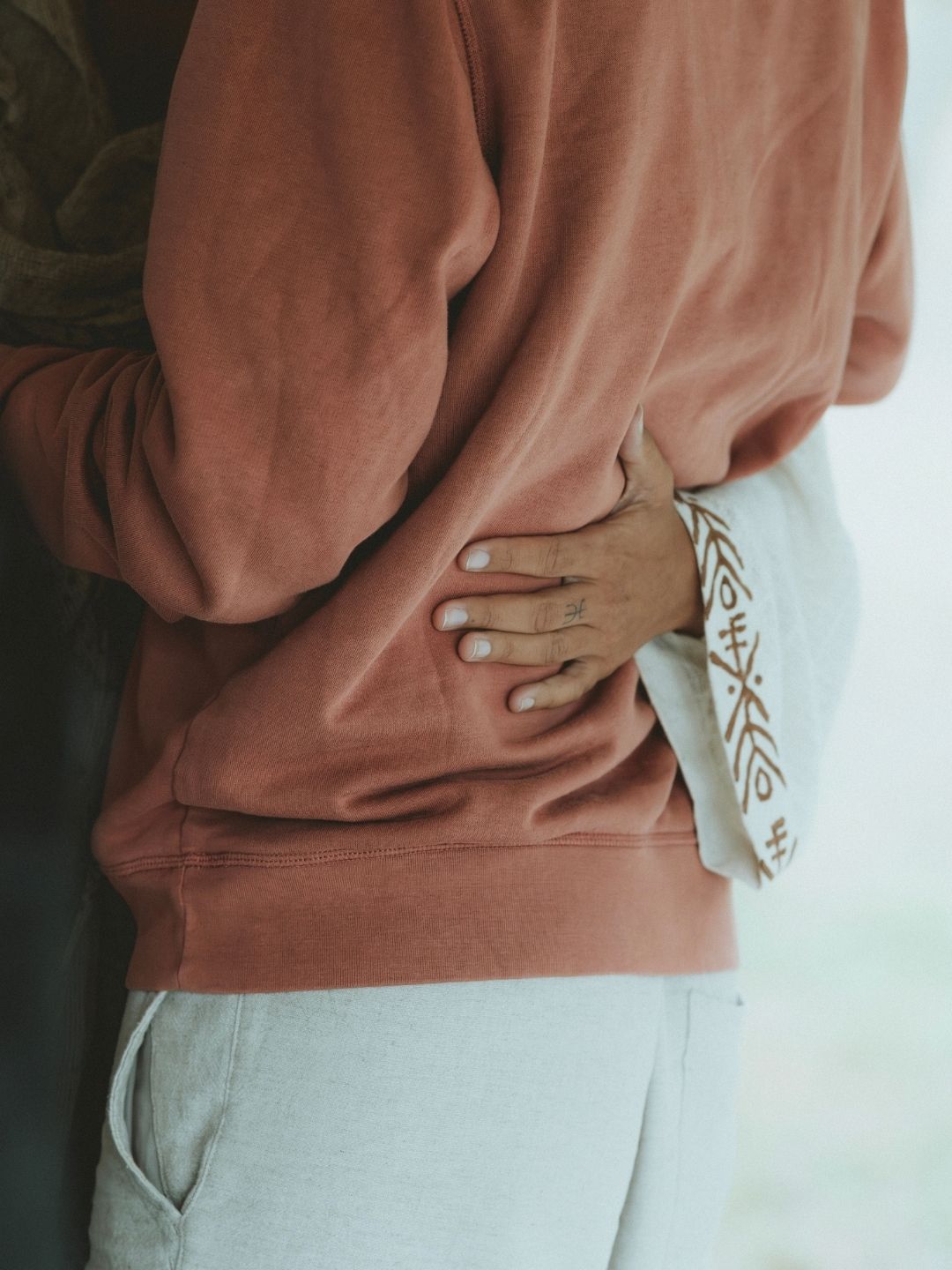 Un geste de soutien posé sur le dos d’un participant pendant une constellation familiale, représentant l’ancrage, le soin énergétique et la libération émotionnelle.